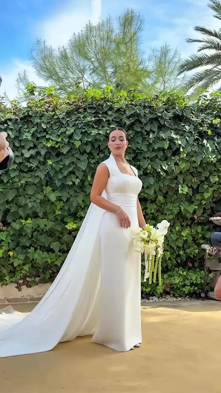 Novia de blanco delante de un muro de hiedra